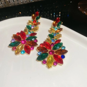 Close-up of colorful crystal flower earrings with vibrant stones on a white ceramic tray