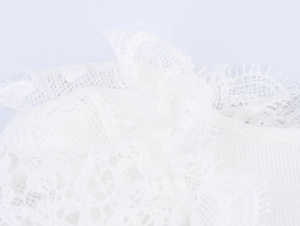 Detailed macro view of white floral lace pattern and ribbed knit fabric on the bodysuit