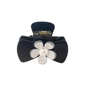Detail of mini black hair claw clip featuring a white daisy flower and pearl accent