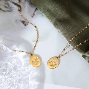 Elegant gold cat paw pendant necklace with textured chain on silk background