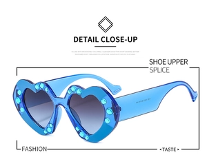 Detail close-up of heart-shaped blue sunglasses with sparkling rhinestone embellishments