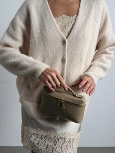 Dettaglio borsa beige in pelle a grana e abito sottoveste in seta con pizzo raffinato
