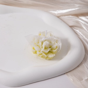Detail of flower-shaped aromatherapy candle in cream white on a champagne satin background
