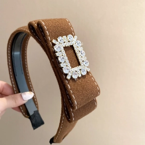 Close-up of brown velvet headband with white stitching and luxury rectangular crystal buckle