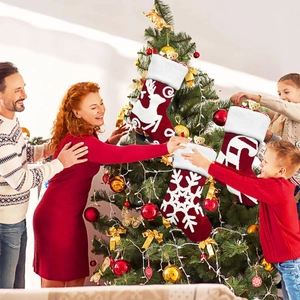 Happy family decorating Christmas tree with embroidered plush red stockings