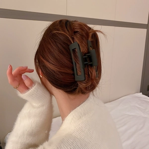 Gros plan d'une grande pince à cheveux géométrique noire mate sur cheveux bruns