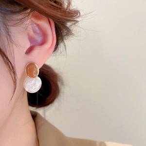 Detail view of retro geometric earrings with amber resin and white marble pendant on model