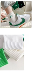 Close-up of cotton sports socks with green NA embroidery paired with white sneakers