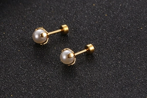 Macro shot of gold stainless steel stud earrings featuring small white pearls