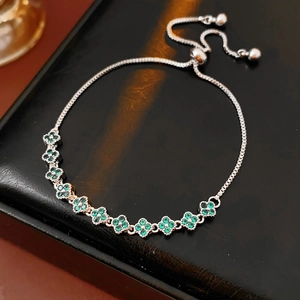 Detail of adjustable silver clover bracelet with green zircon stones on black leather