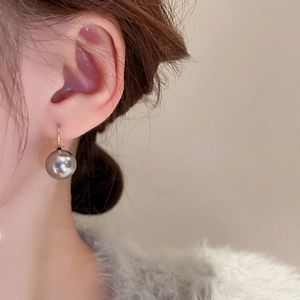 Detailed close-up of an elegant dark grey pearl earring with minimalist gold hook
