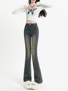 Détail d'un jean évasé gris à taille haute avec genou déchiré et effet délavé vintage