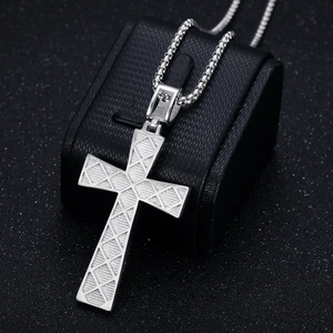 Pendentif croix hip hop en argent avec texture géométrique sur un présentoir à bijoux