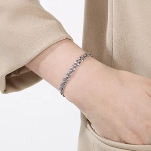 Close-up of silver-plated grid watch strap bracelet on wrist with elegant outfit