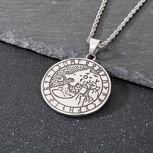 Macro detail of silver Viking Fenrir wolf pendant with runic letters on black rock