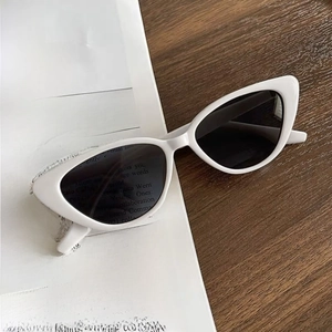 Classic white cat eye sunglasses with dark lenses on a vintage newspaper and wood desk