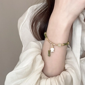 Detail of bamboo style bracelet with white lily pendant and green jade beads on wrist