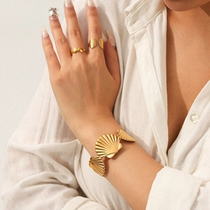Close-up of gold stainless steel shell ring and bracelet set worn by a model