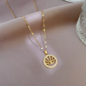 Macro shot of gold Evil Eye necklace with zircon crystals on soft pink silk background