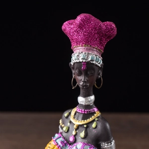 Close-up of African woman figurine with pink glitter headwrap and gold jewelry detail