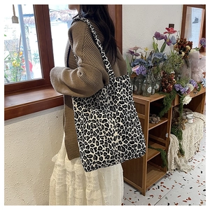 Lifestyle shot of large leopard print canvas tote bag carried on a shoulder indoors