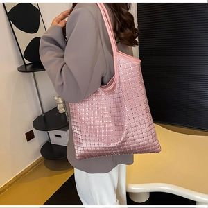 Close-up of pink satin shoulder bag with silver rhinestone grid pattern and long strap