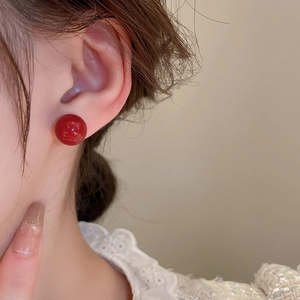 Macro side view of model wearing minimalist red spherical gold plated silver stud earrings