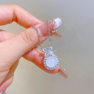 Macro detail of silver bow pendant with centered pearl and sparkling crystal accents