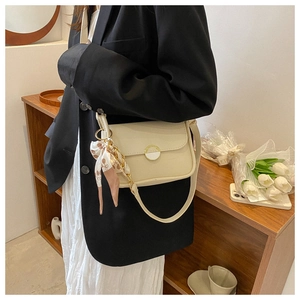 Close-up of cream square shoulder bag with gold round lock and floral silk scarf detail
