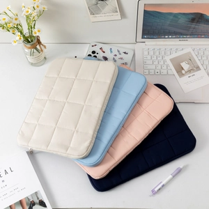 Quilted protective laptop sleeves in pastel colors displayed on a white desk