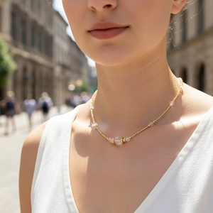 Detail of beaded gold chain necklace with white stones on female model in outdoor setting