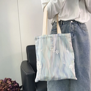 Détail d'un sac cabas en toile avec dégradé pastel et broderie de fleurs en mesh 3D