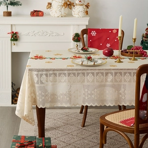 Close-up of beige lace Christmas tablecloth featuring snowflake and bell patterns