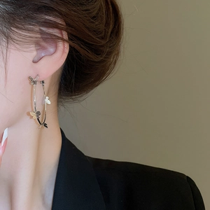 Detailed close-up of large silver hoop earrings featuring sparkling 3D butterfly charms