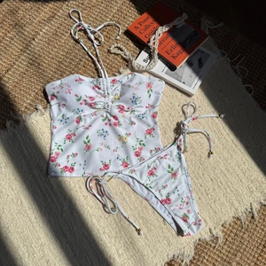 Close-up of floral print bikini with halter top and side-tie bottoms on beach mat
