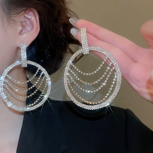 Gros plan de boucles d'oreilles à pompons ronds serties de strass sur monture dorée