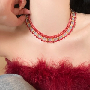 Close-up of a handmade ethnic choker with red and gold beads in a wavy pattern