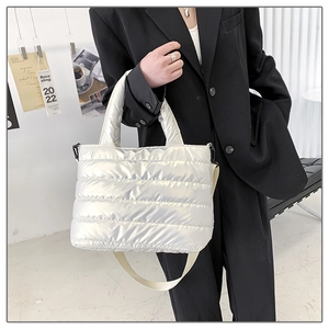Silver quilted down tote bag with metallic finish shown styled with a black blazer