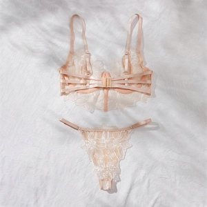 Detail of peach lace lingerie set with floral embroidery on soft white plush background