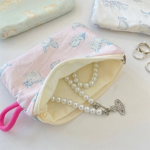 Close-up of fabric coin purse with cat print storing a pearl necklace inside
