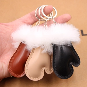 Close-up of winter glove-shaped faux leather keychains with white plush fur trim