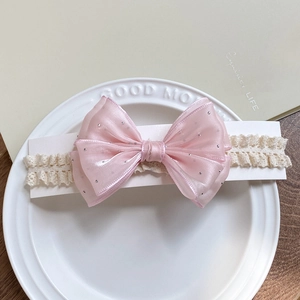 Pink polka dot bow headband with beige lace for newborn baby girls on a white plate