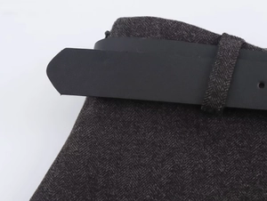 Detail of grey herringbone wool skirt waist featuring a black leather belt and loops