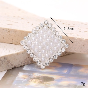 Macro shot of silver pearl brooch with rhinestones on a stone texture background