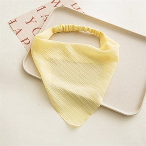 Detail of yellow floral chiffon scrunchie with soft fabric texture on a neutral tray