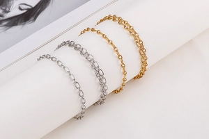 Close-up of classic minimalist gold and silver curb chains on a white pedestal stand