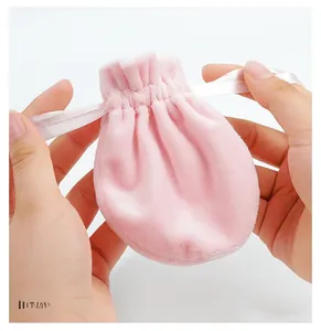 Close-up of soft light pink velvet drawstring pouch held in hands showing fabric texture