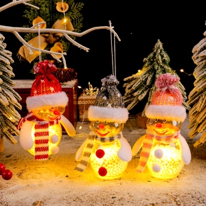 Three glowing LED snowman ornaments in red, pink, and grey on a snowy Christmas scene