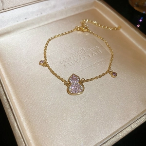 Macro shot of 18k gold plated gourd bracelet with pink zircons on silk lining