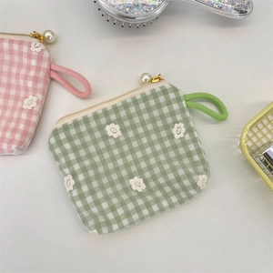 Détail de broderie florale sur tissu à carreaux avec fermeture éclair élégante en perle